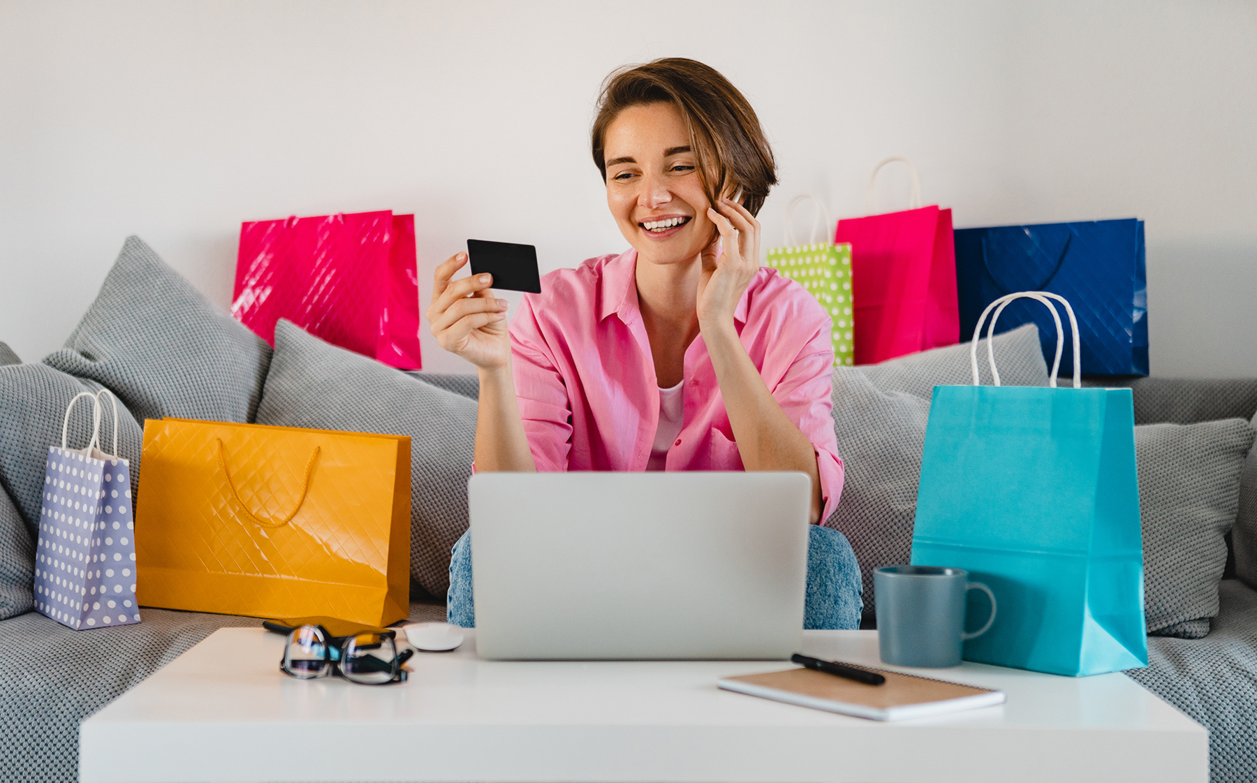 happy smiling woman in pink shirt on sofa at home shopping online